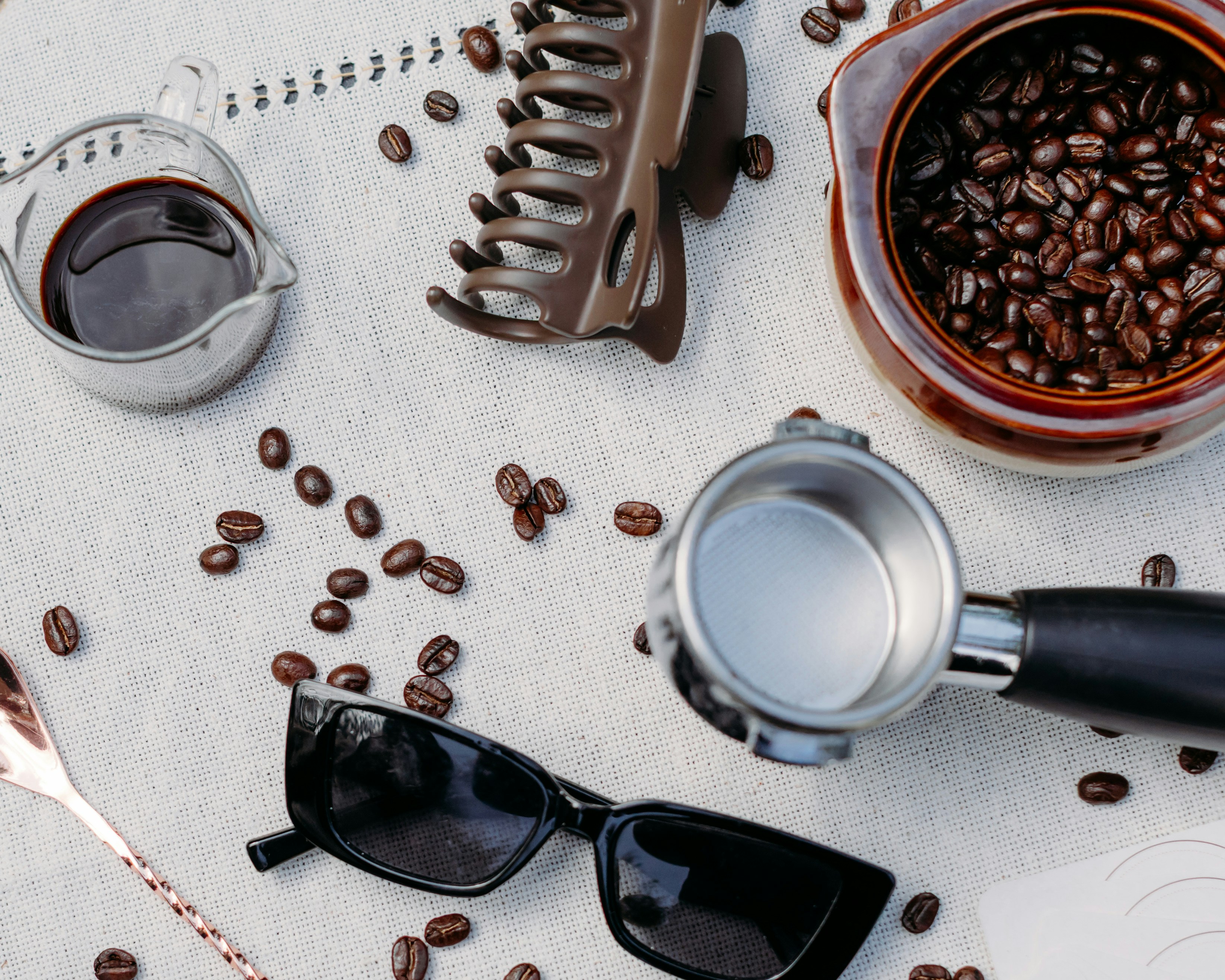 Coffee beans and espresso machine parts on a surface.