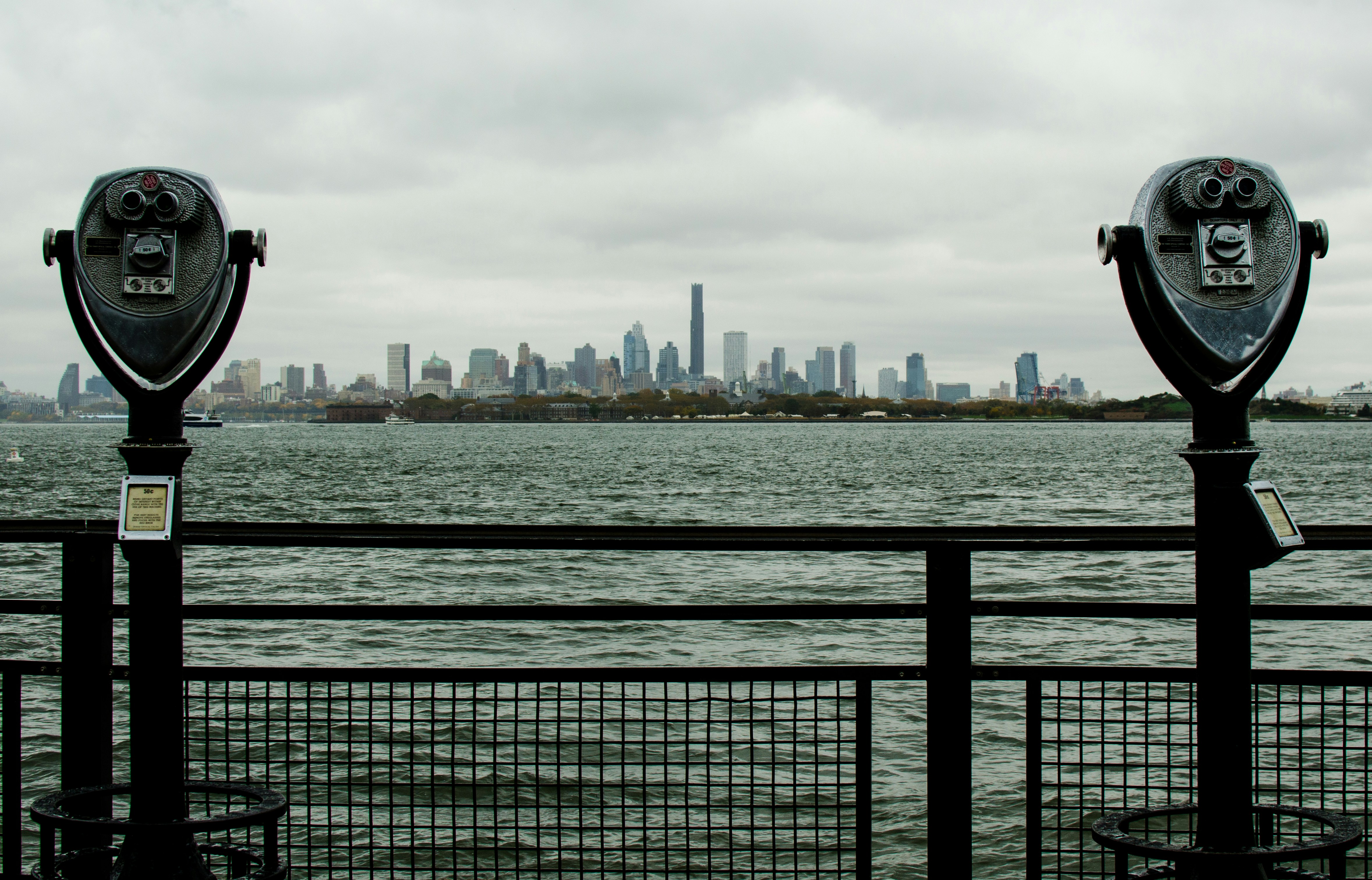 Two viewing binoculars with city skyline across water