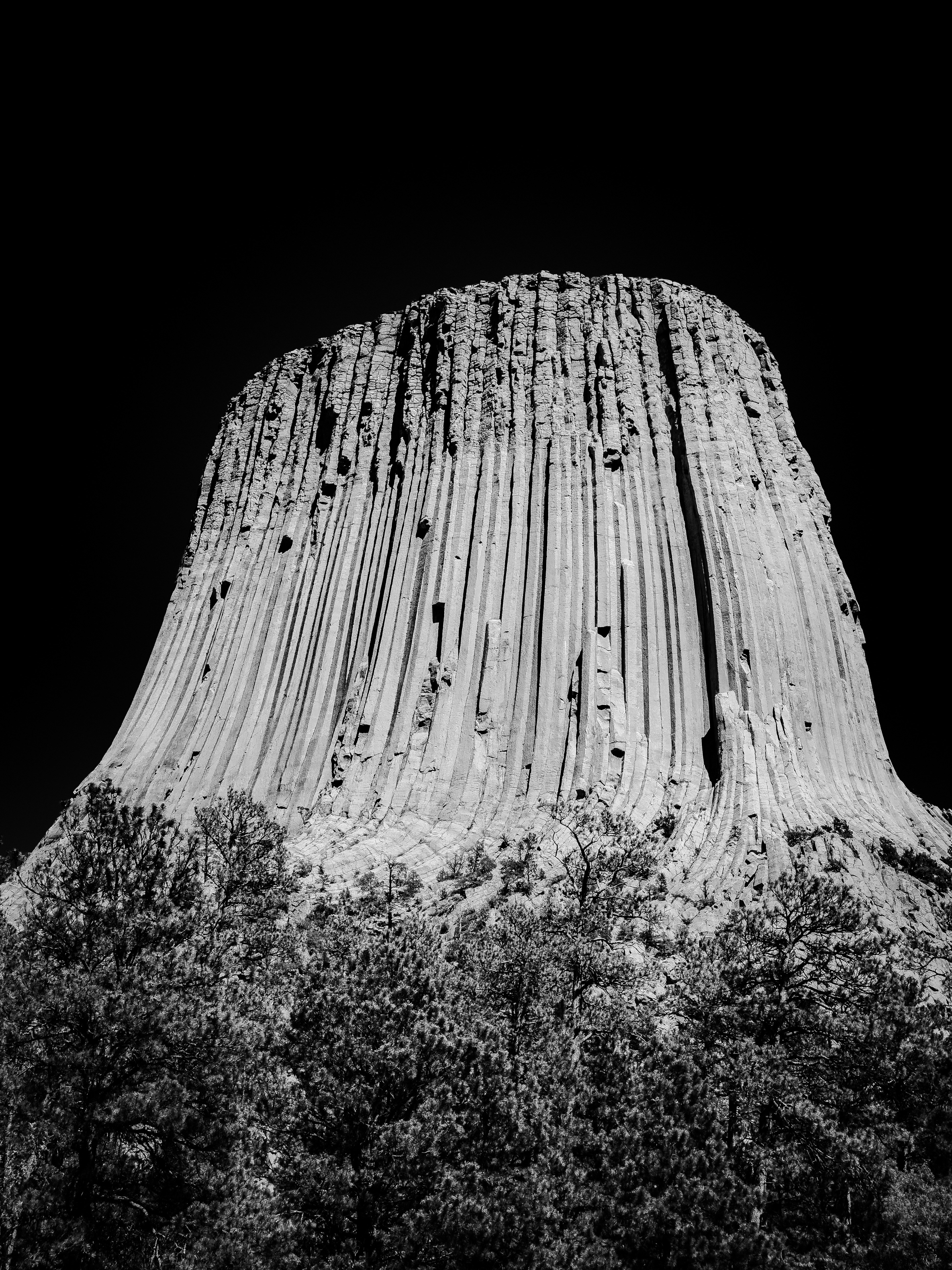 Devils tower national monument against a black sky