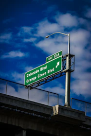 Green highway sign with directions under blue sky