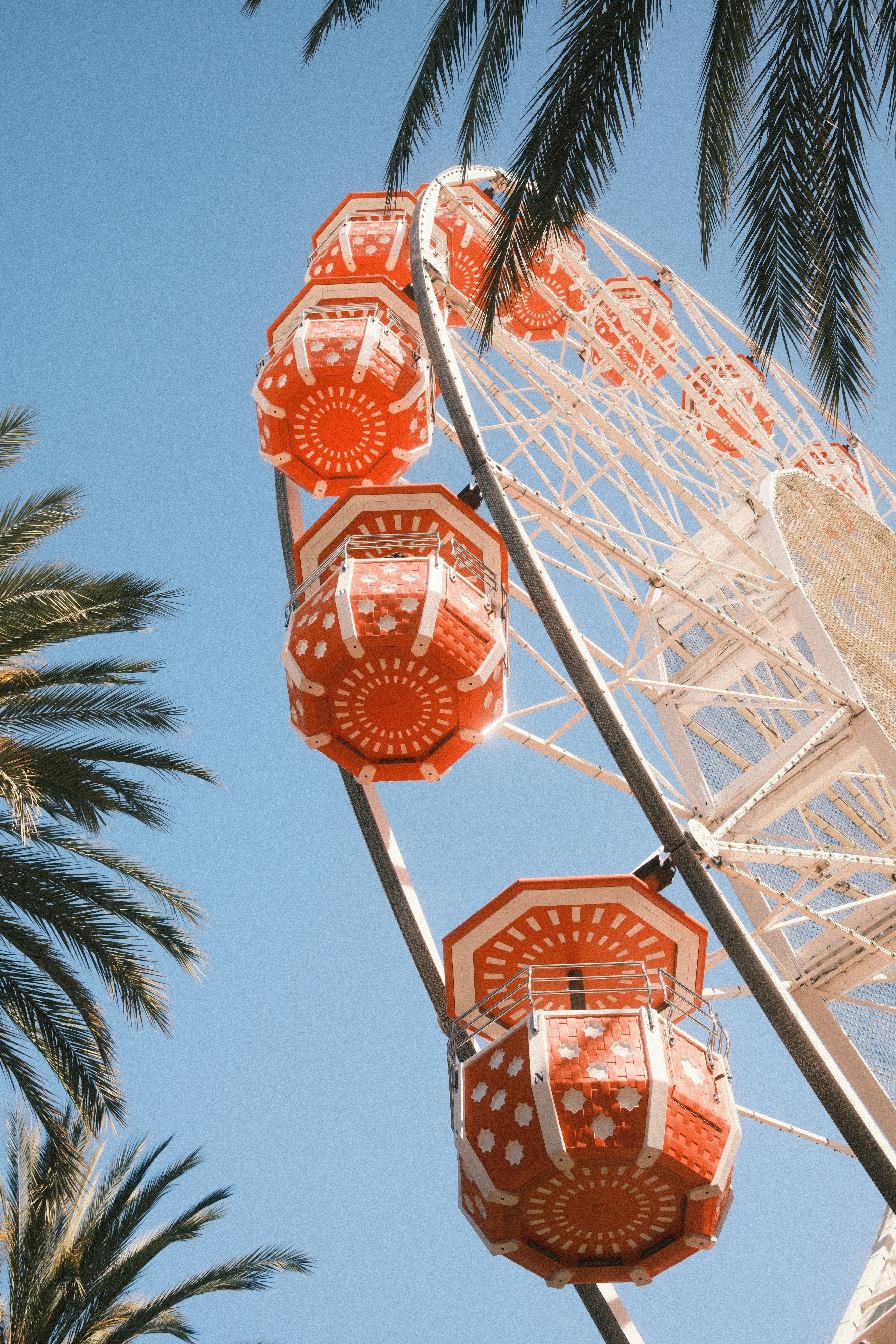Ferris wheel with orange cabins against blue sky