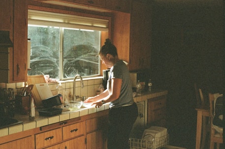 Woman washing dishes at a kitchen sink.