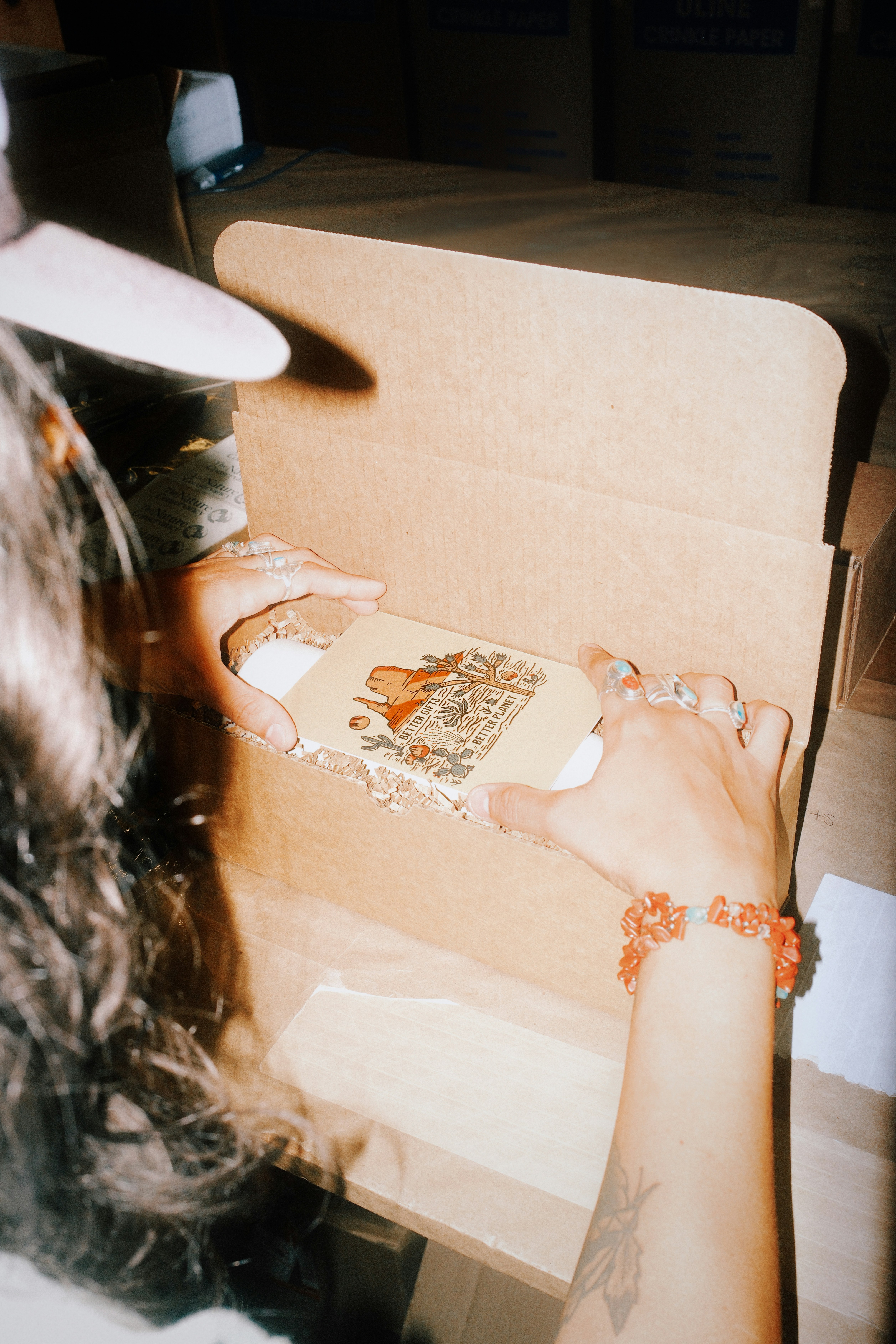 Hands opening a cardboard box with a decorative item inside.