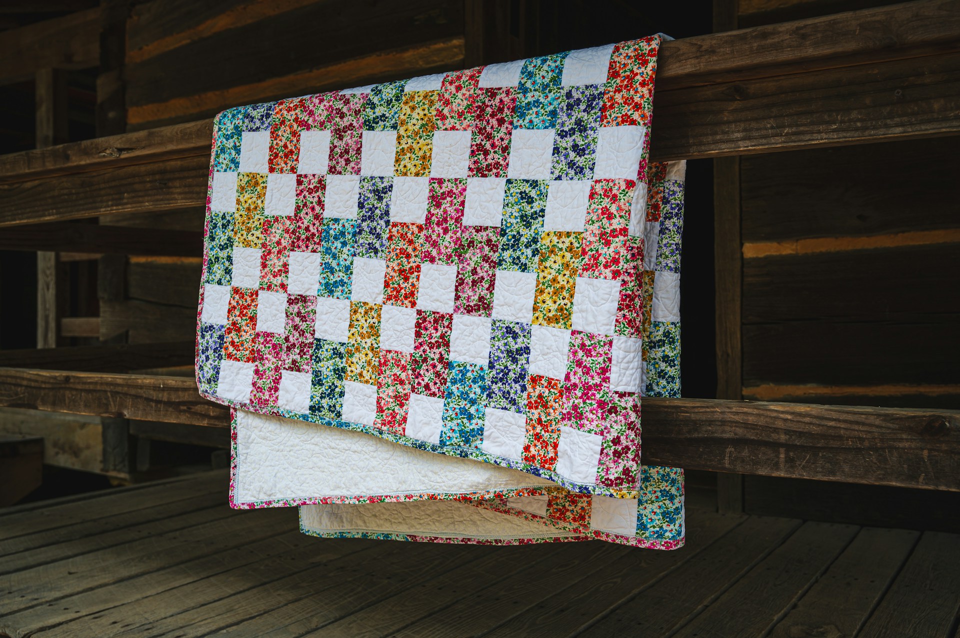 Colorful checkered quilt draped over wooden railing