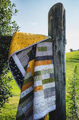 Colorful quilt draped over a wooden fence post.