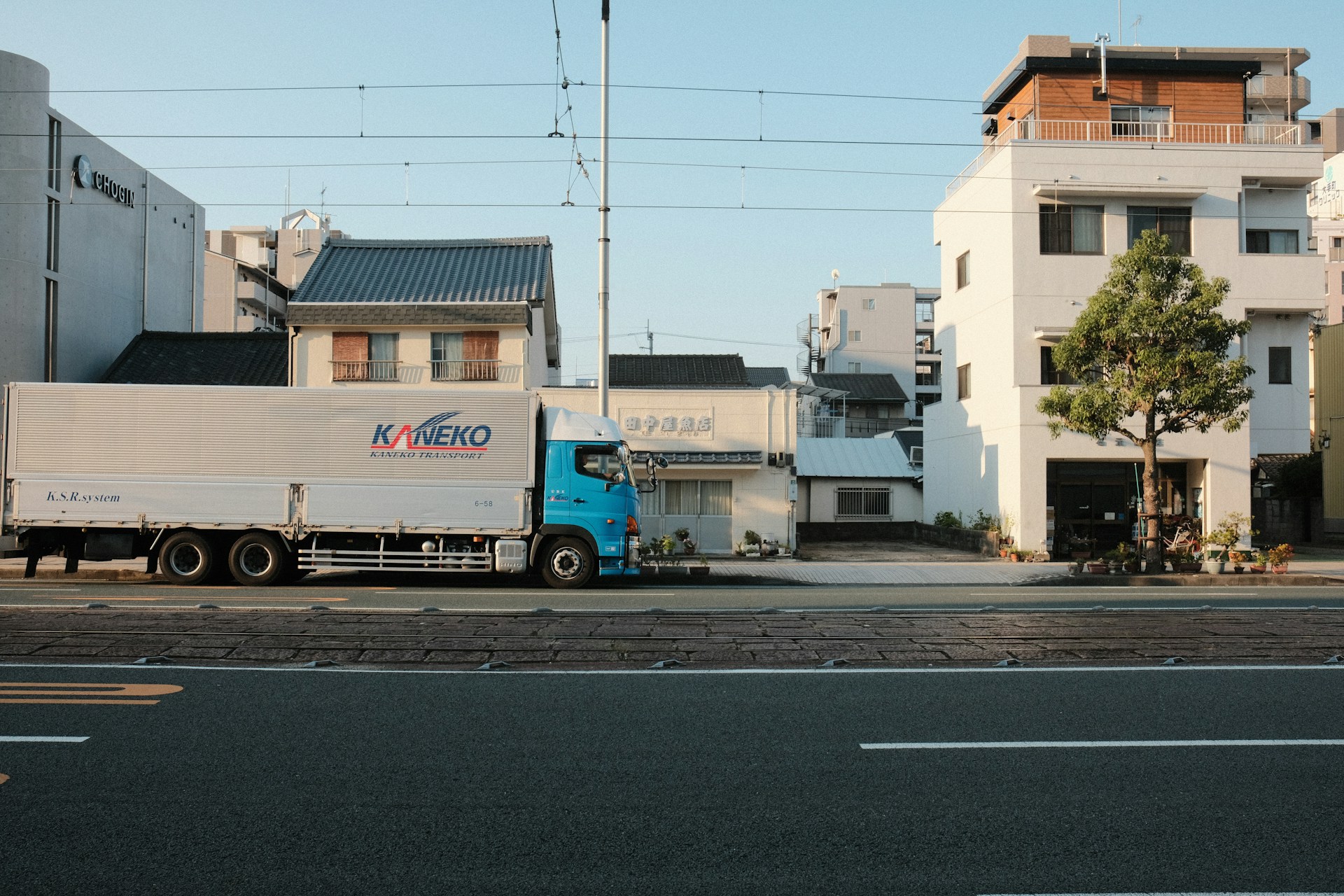 Truck driving down a street with buildings.