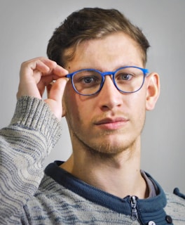 Man adjusting blue-rimmed glasses with his hand