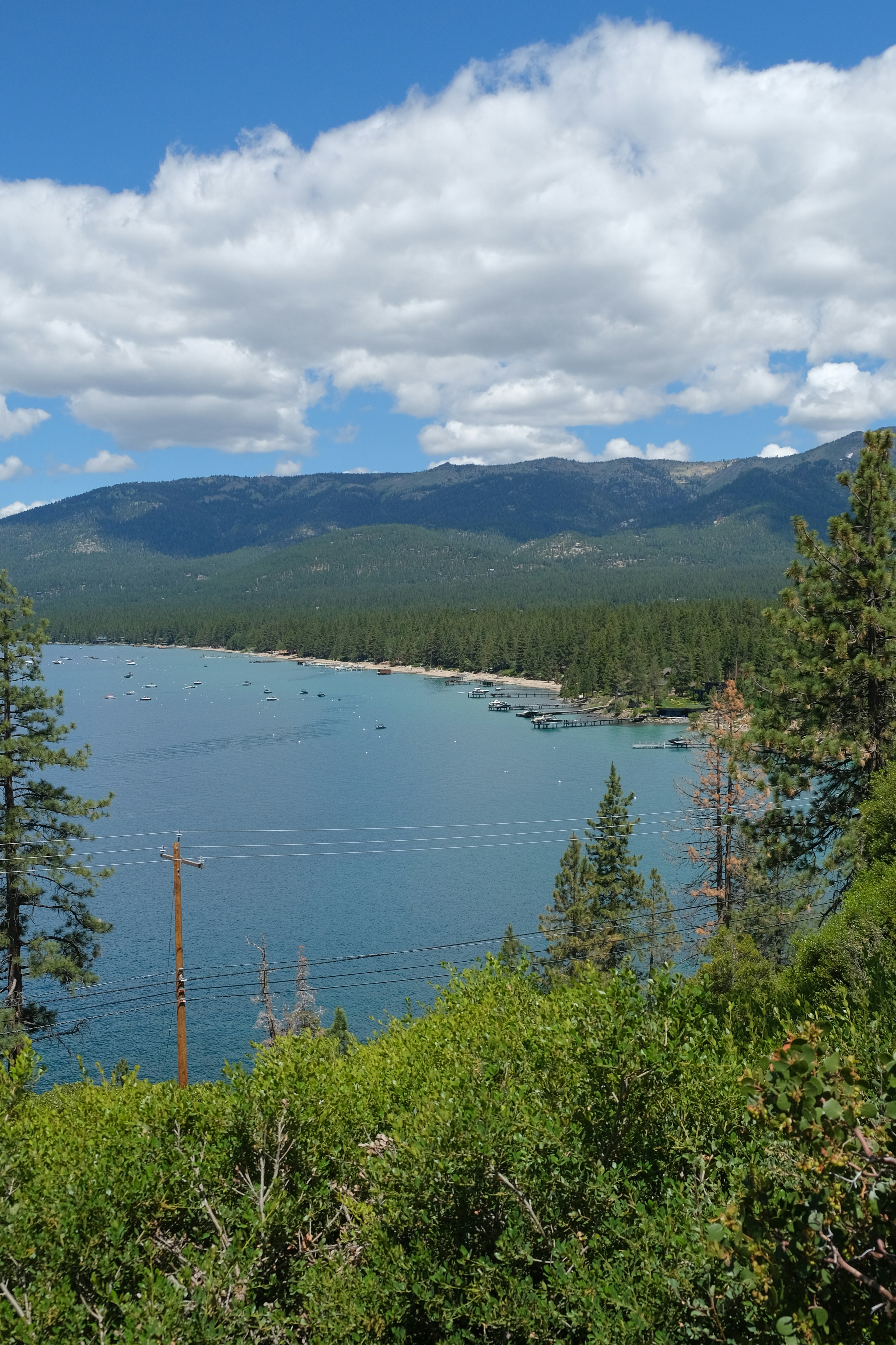 Lake with boats and forested mountains under clouds