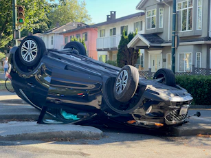 A car overturned on its side on a street.