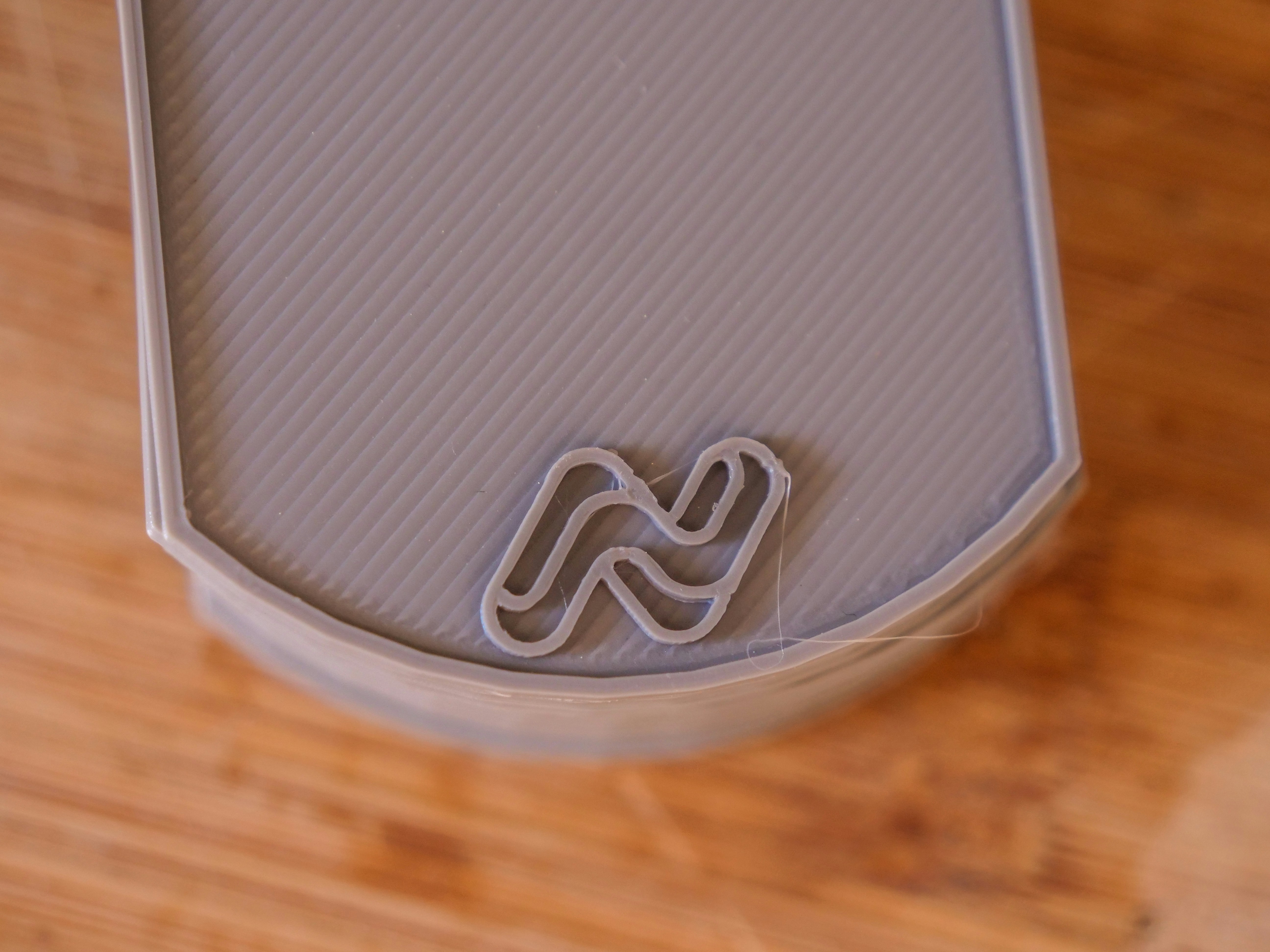 Gray textured surface with a stylized n logo.