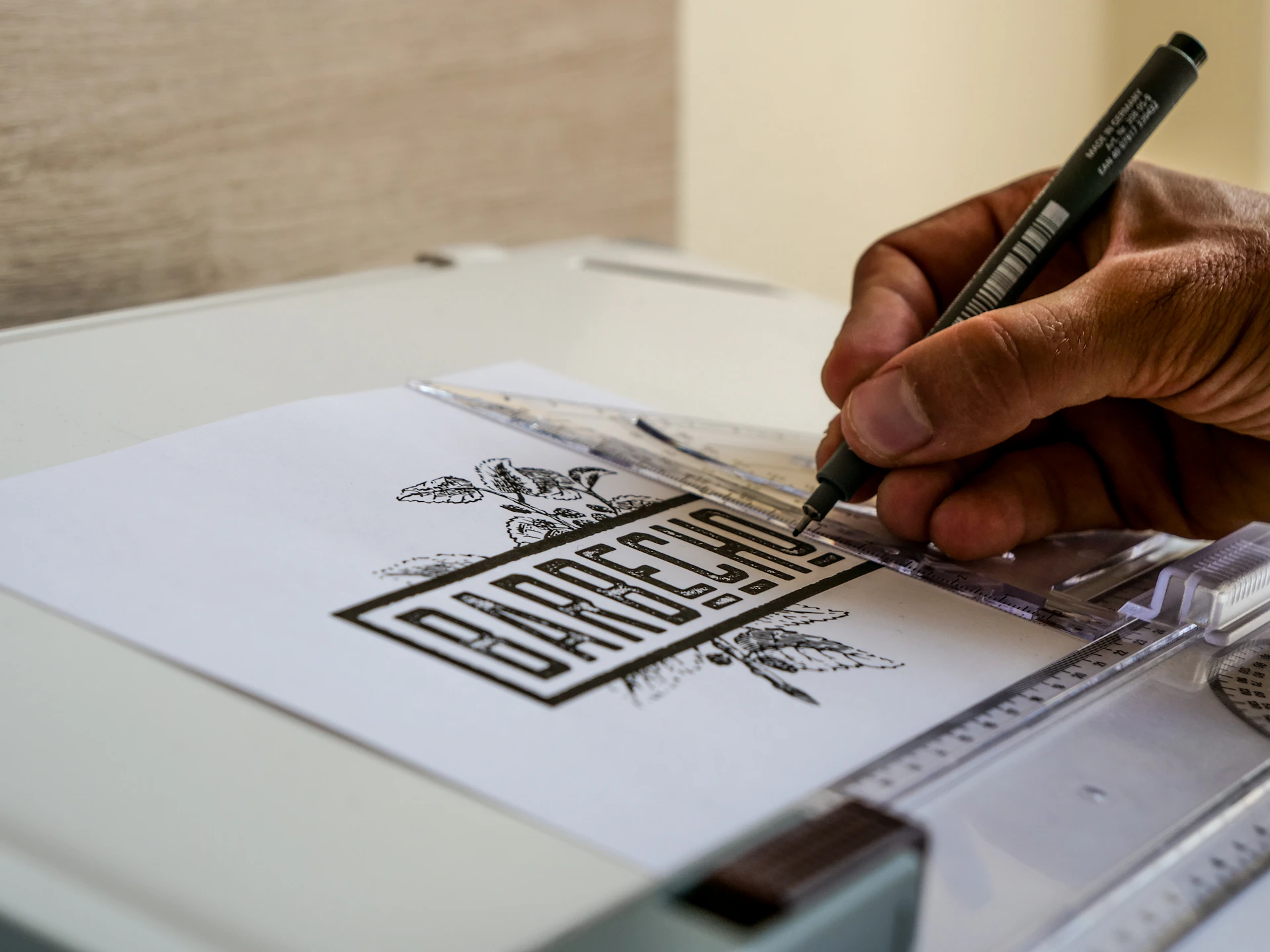 Artist drawing a logo with a pen on paper.