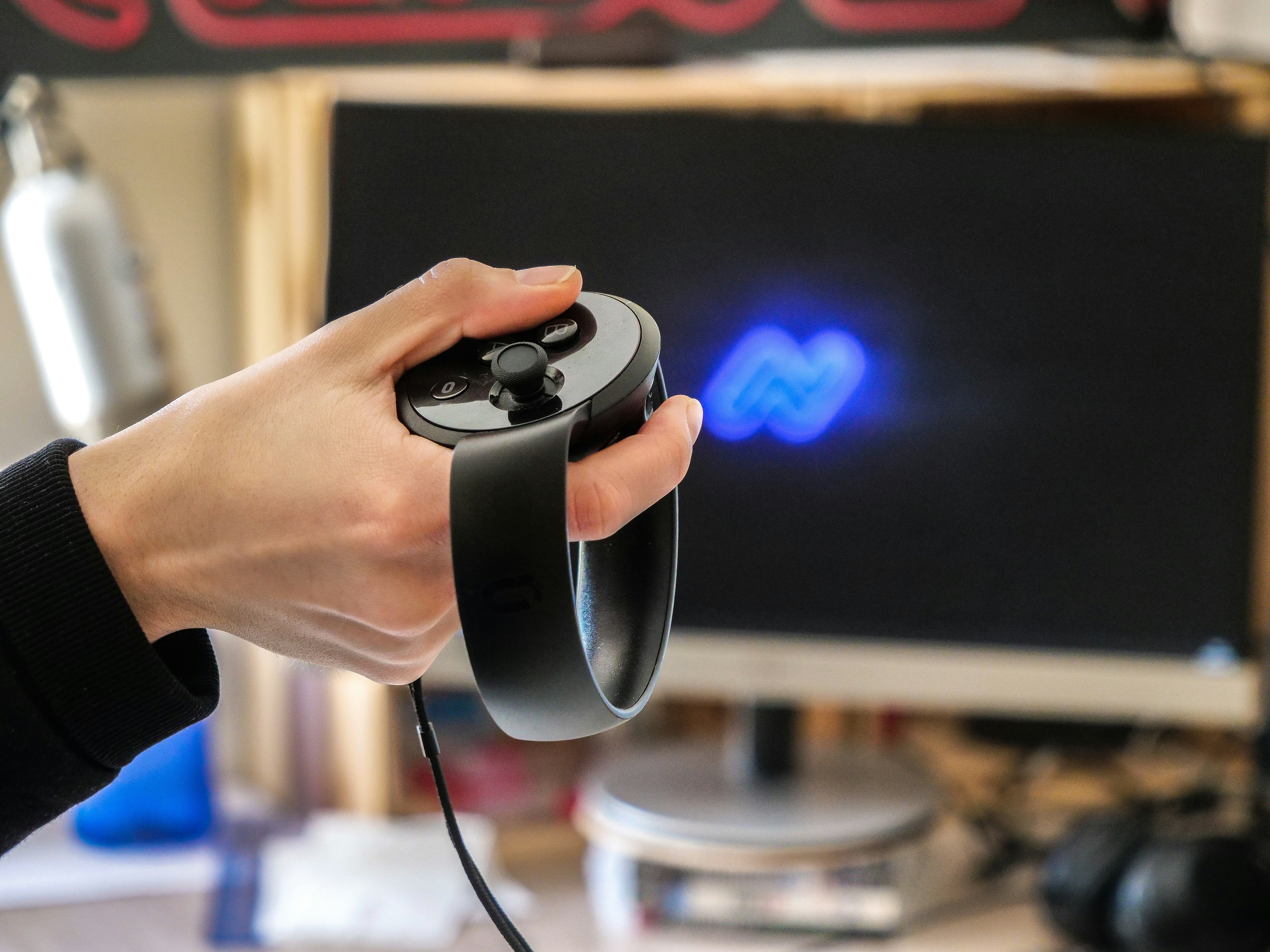 Hand holding vr controller with screen in background