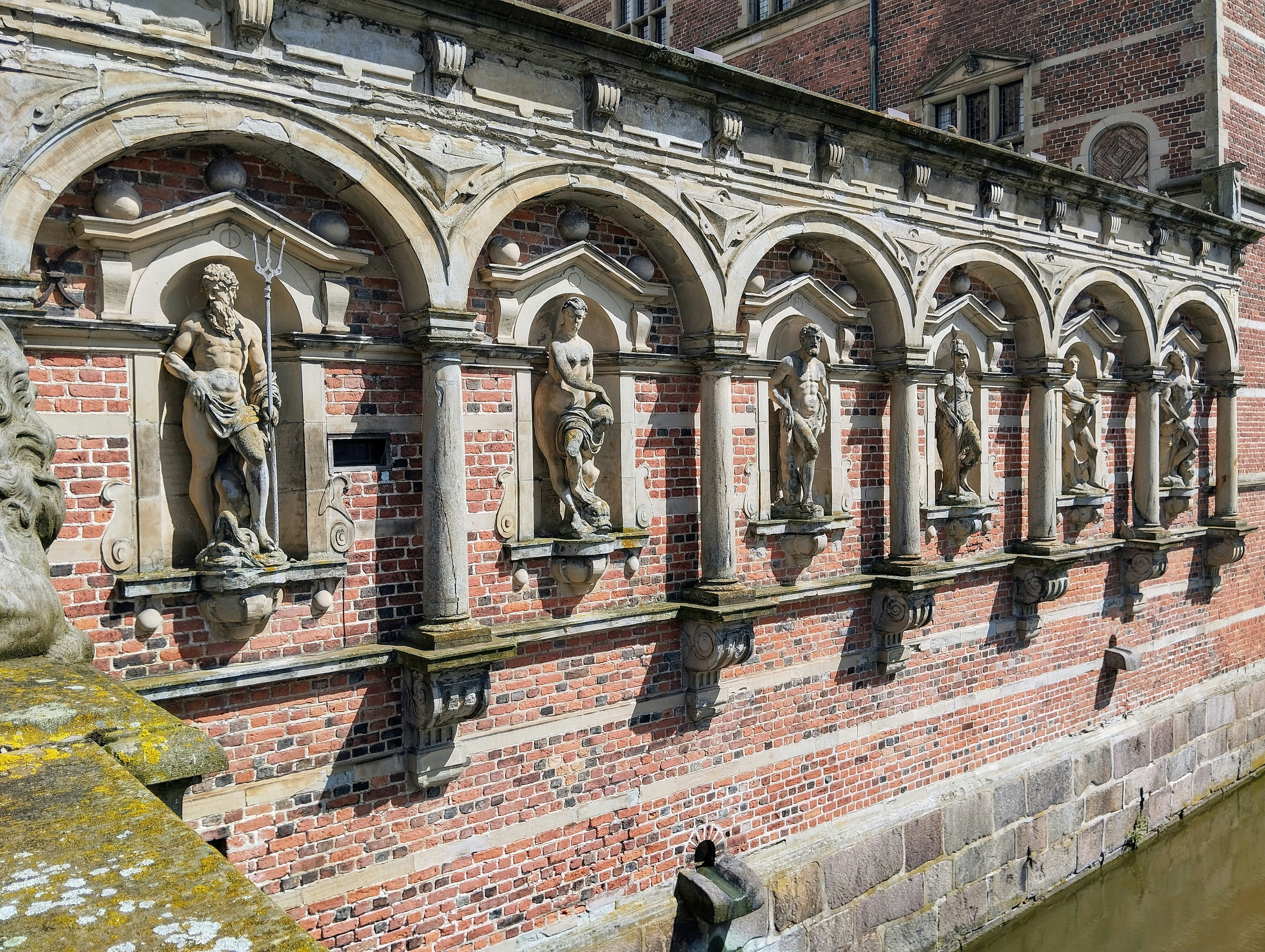 Stone statues adorn a brick building wall
