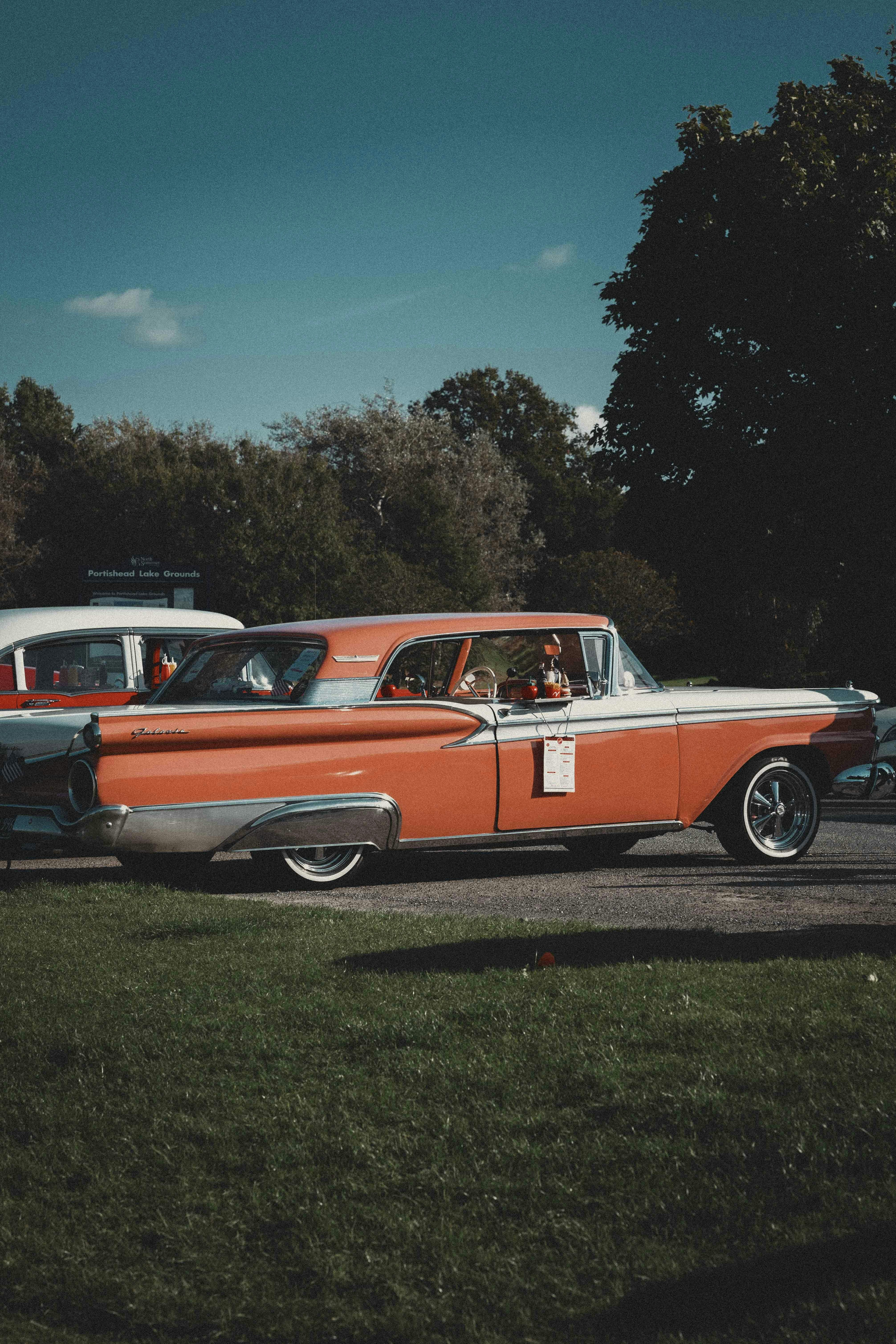 Orange and white vintage car driving on a road