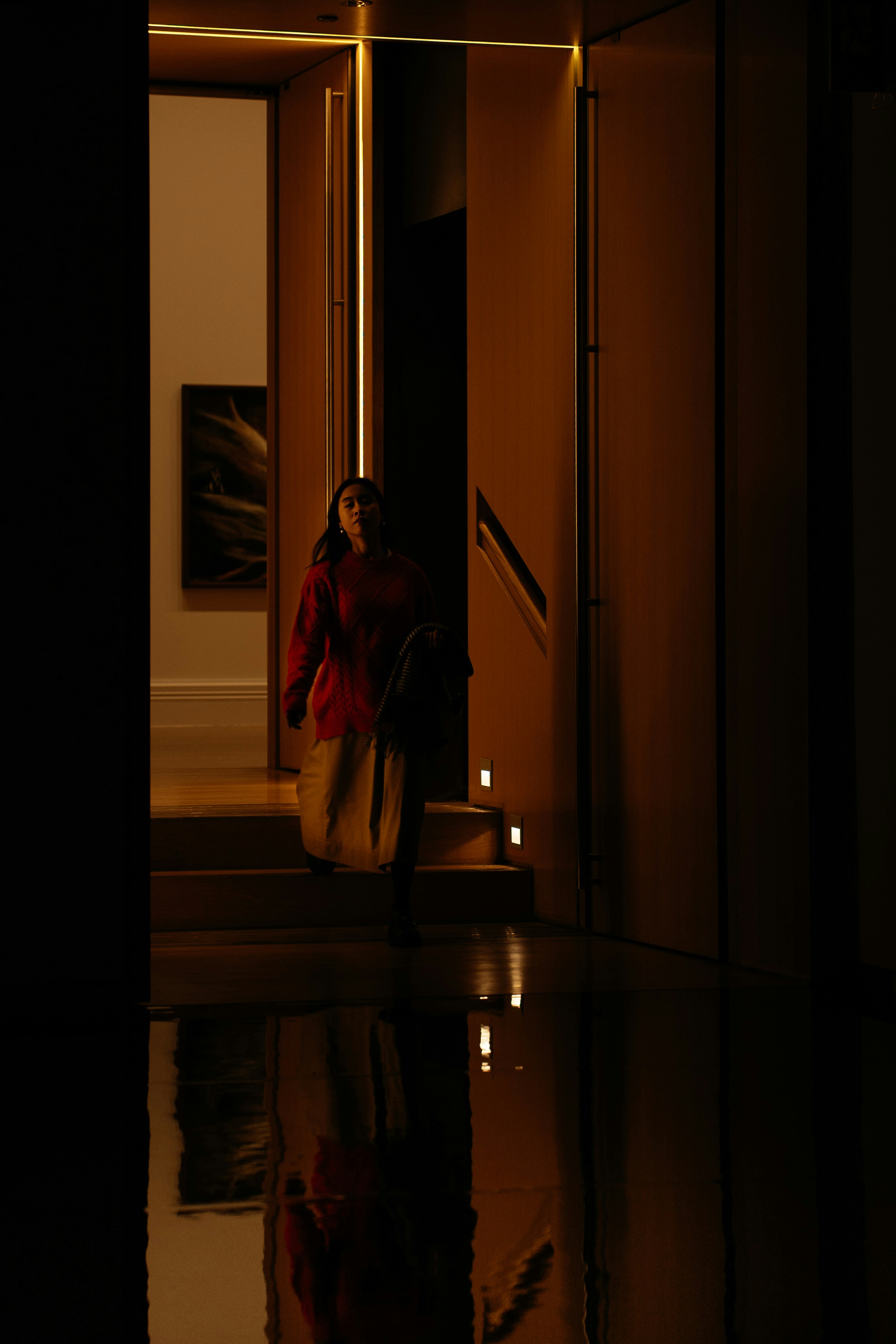 Woman in red coat walks up illuminated stairs