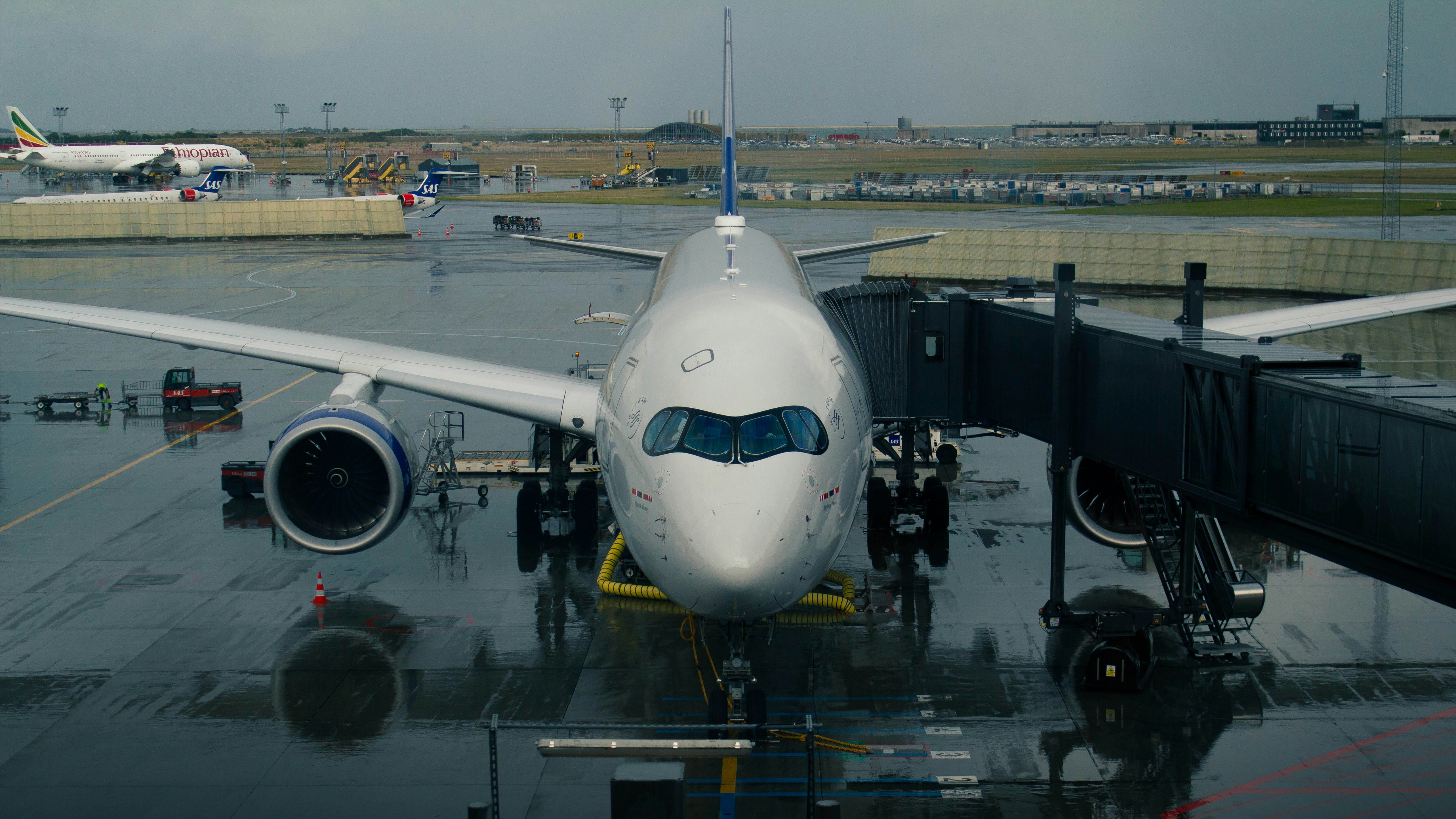Airplane connected to a jet bridge on a rainy day.