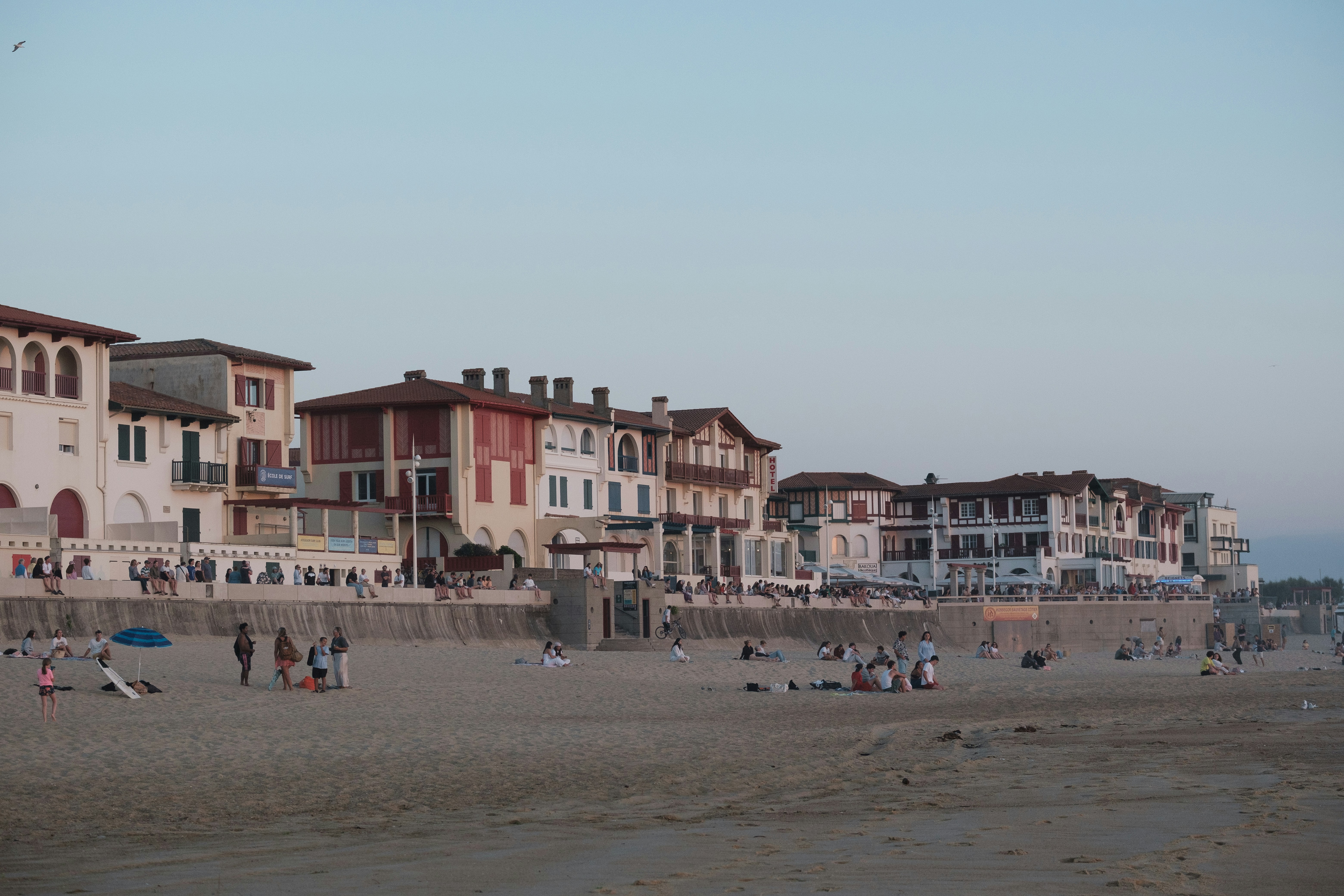 砂浜でくつろぐ人々がいるビーチフロントの建物。