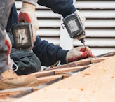 Construction workers using power drills on a roof