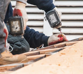 Construction workers using power drills on a roof