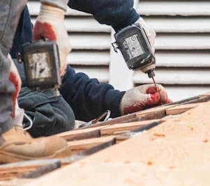 Construction workers using power drills on a roof