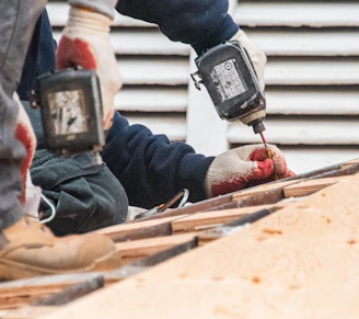 Construction workers using power drills on a roof