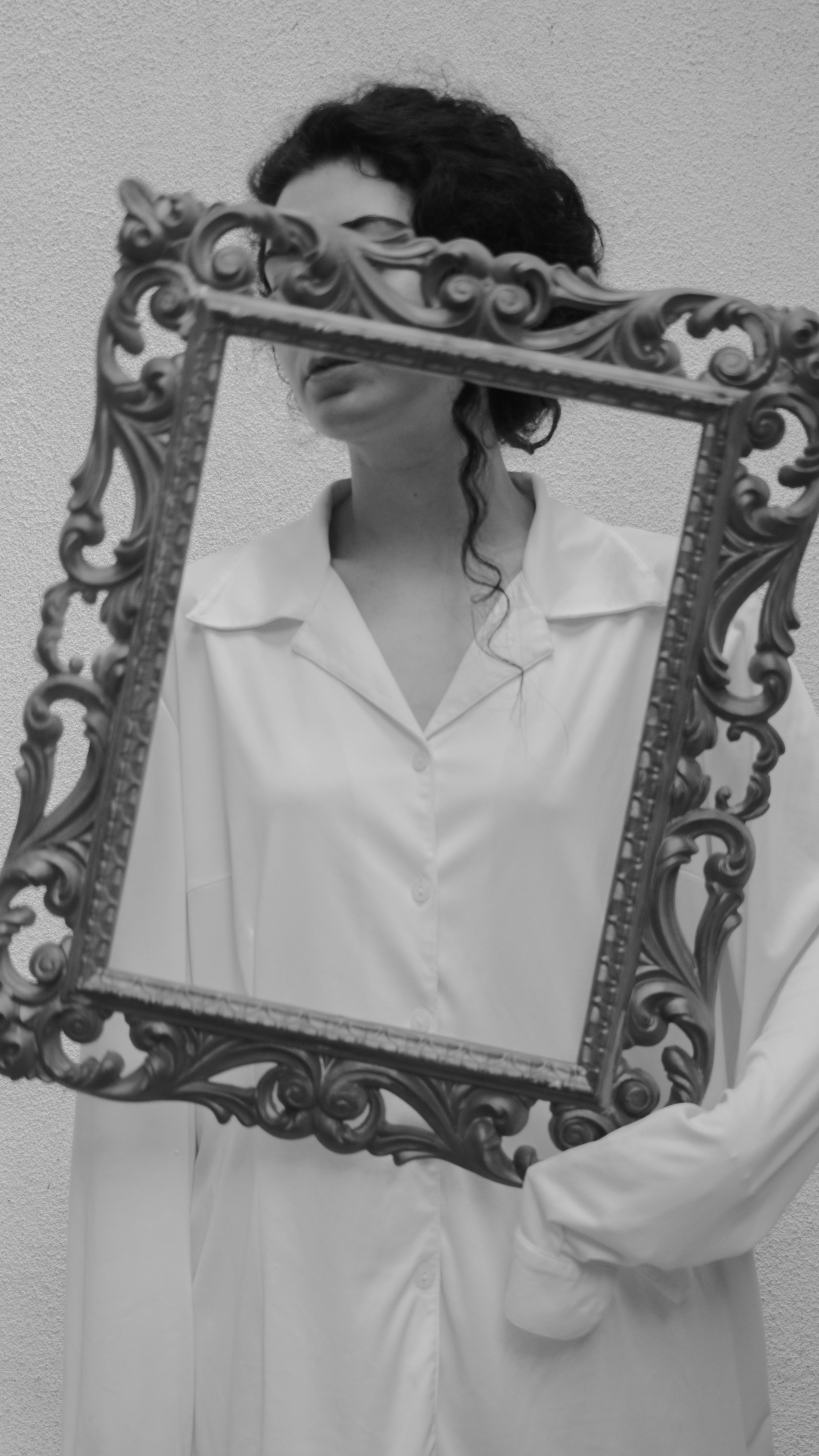 Woman holding ornate frame in front of face