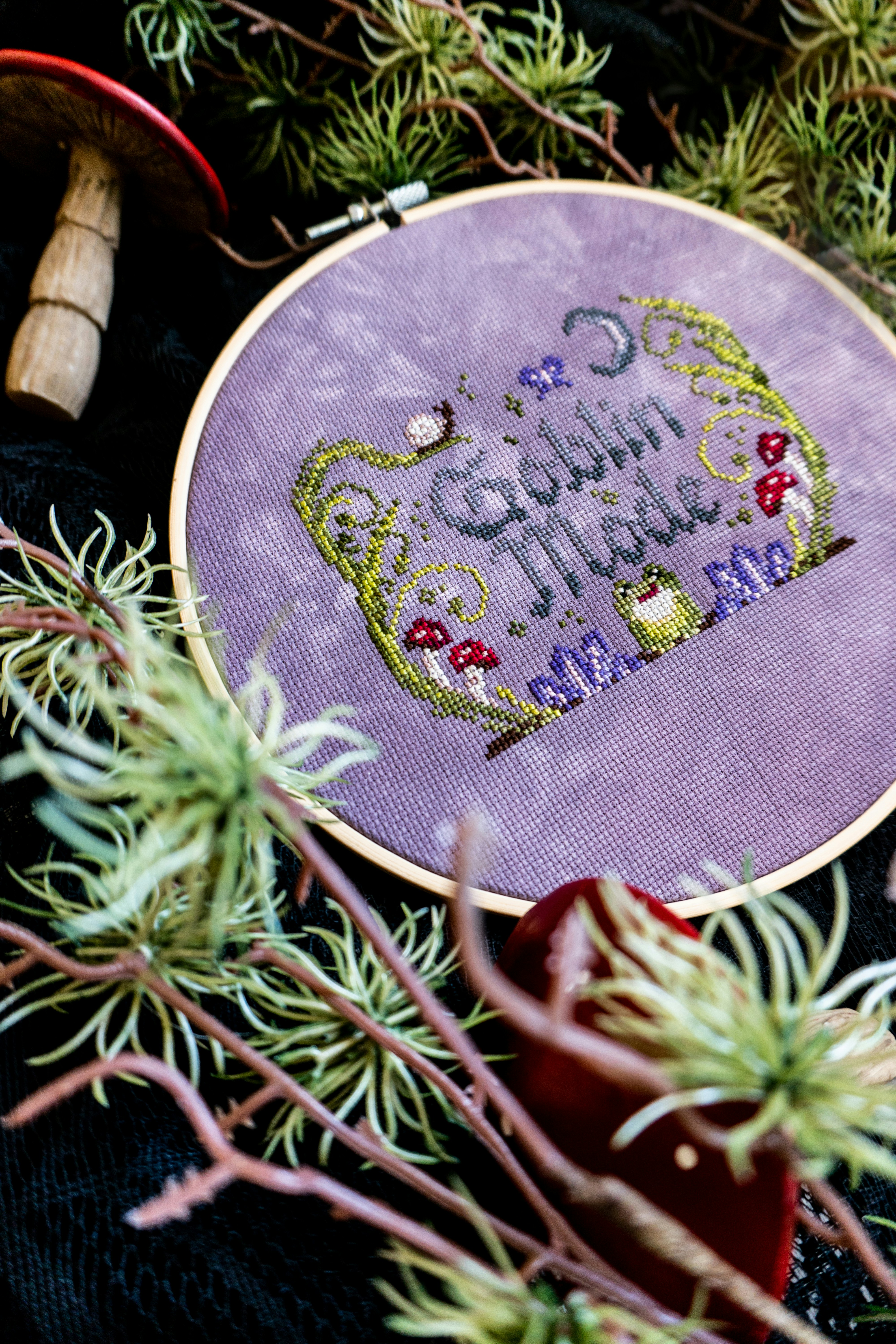 Embroidery hoop with "goblin mode" text and nature elements.