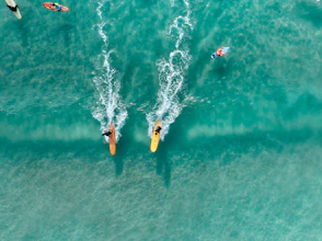 Two surfers race across turquoise ocean waves
