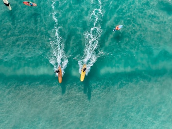 Two surfers race across turquoise ocean waves