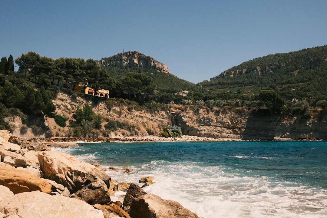 Rocky shoreline with blue ocean and green hills.