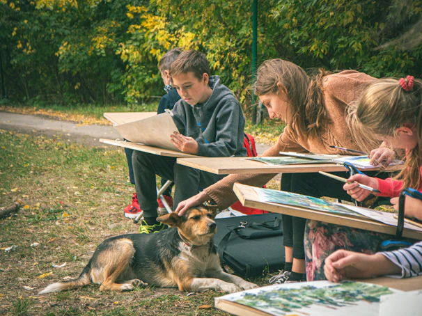 Children drawing outdoors with a dog nearby