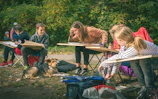 Children learning to draw outdoors with a dog nearby
