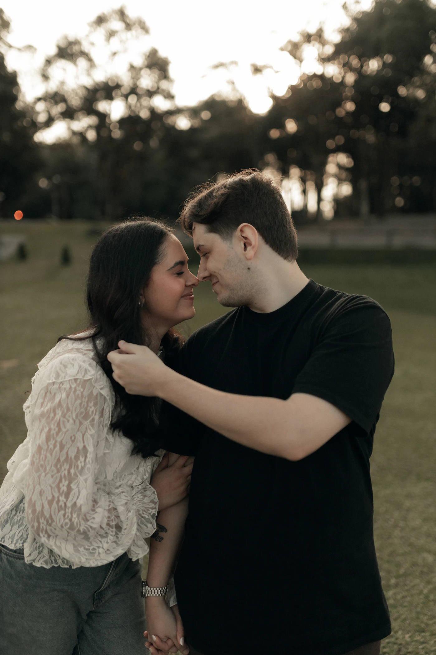 A couple holding each other in a park at sunset
