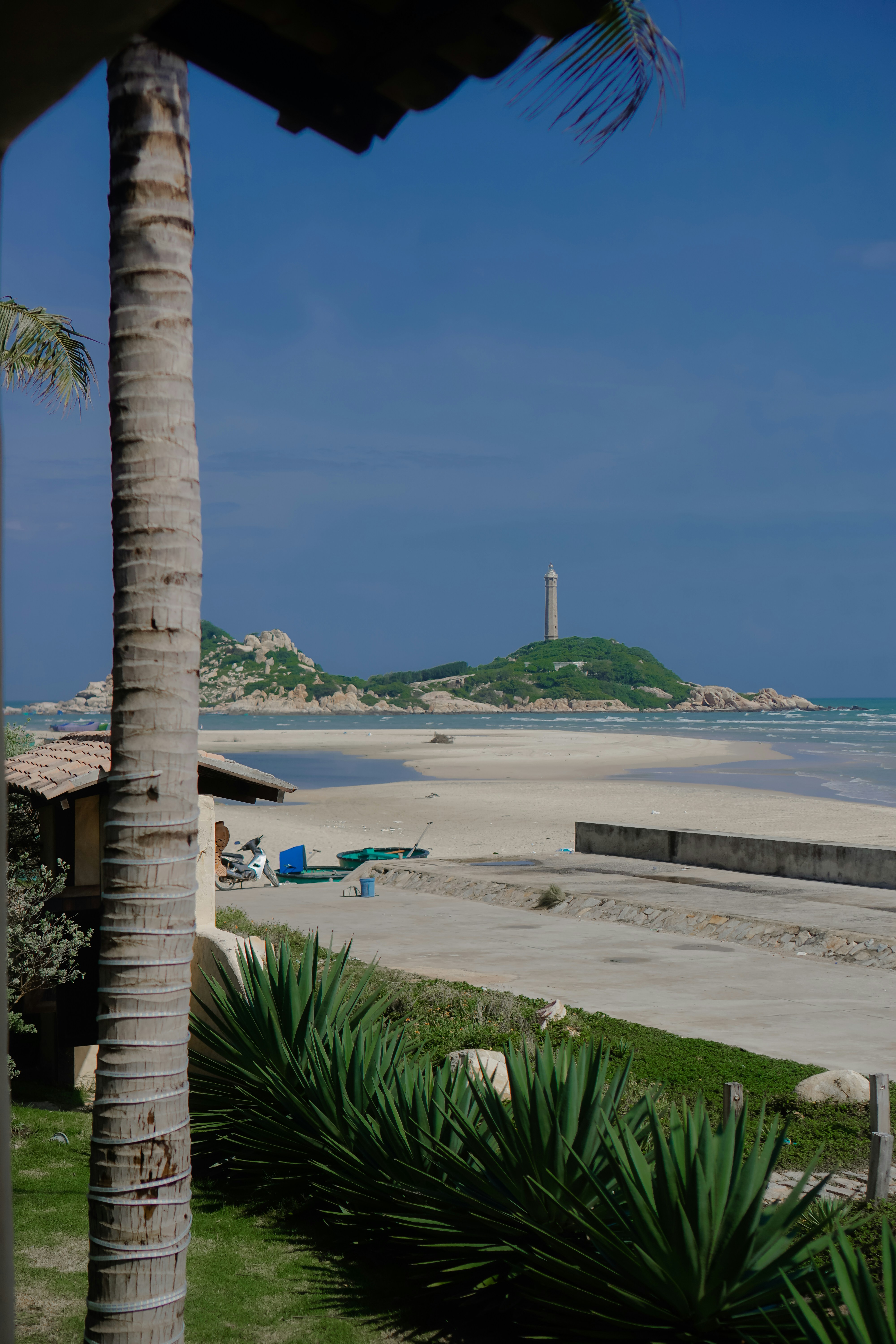 Lighthouse on a distant island over a sandy beach.