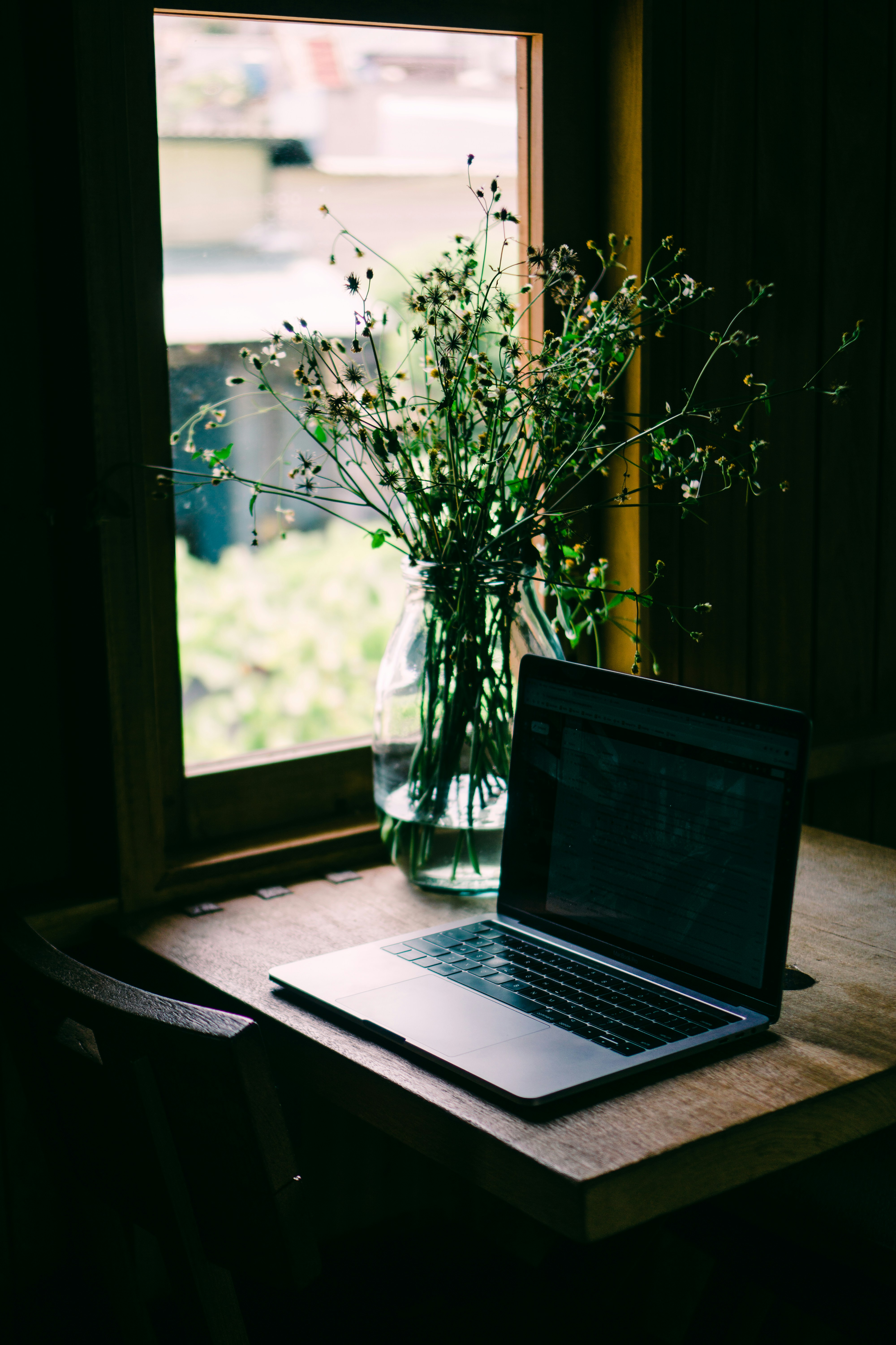 Laptop and flowers by a window