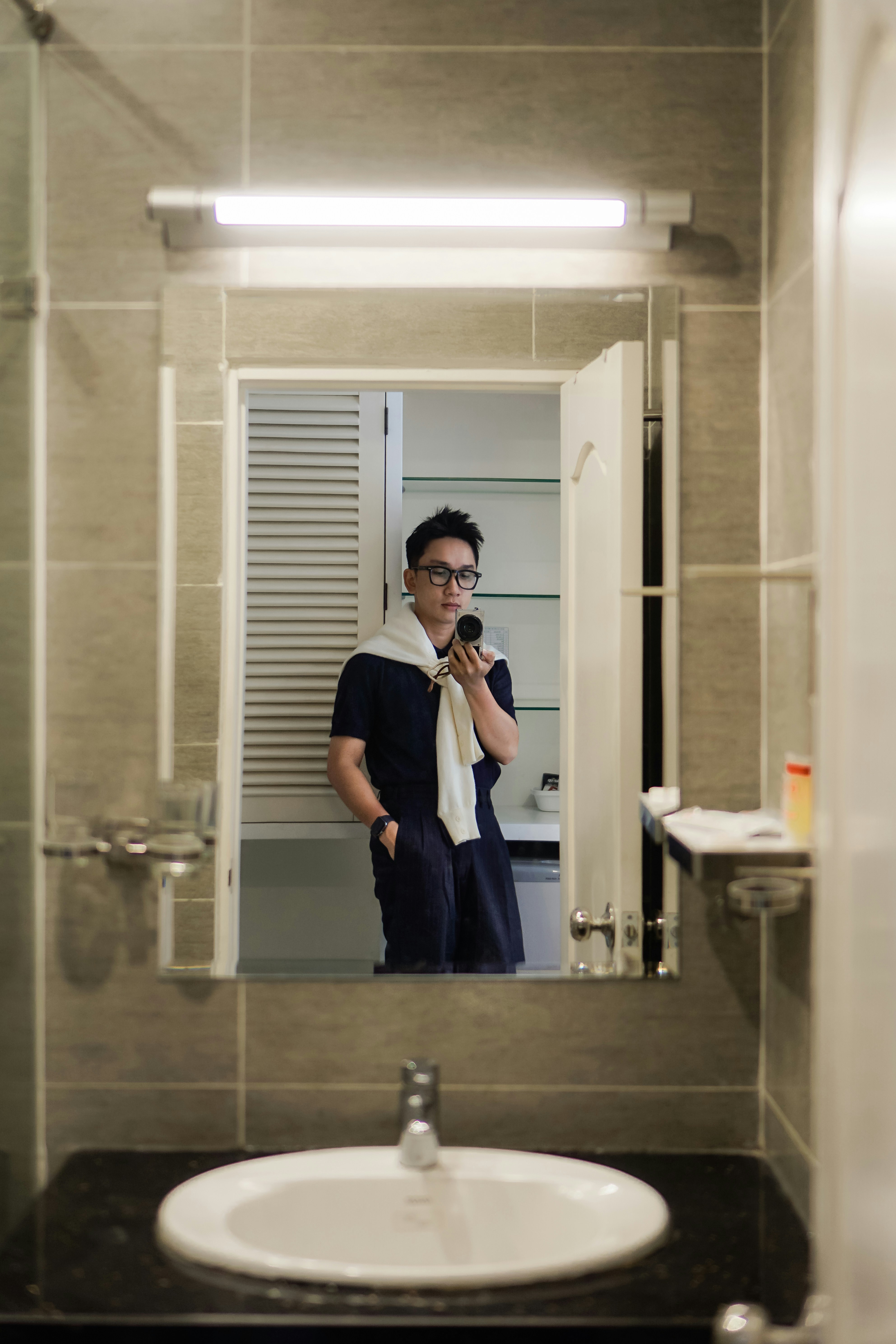 Man takes a selfie in a bathroom mirror.