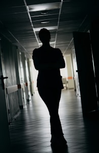 Silhouette of a person standing in a dark hallway.