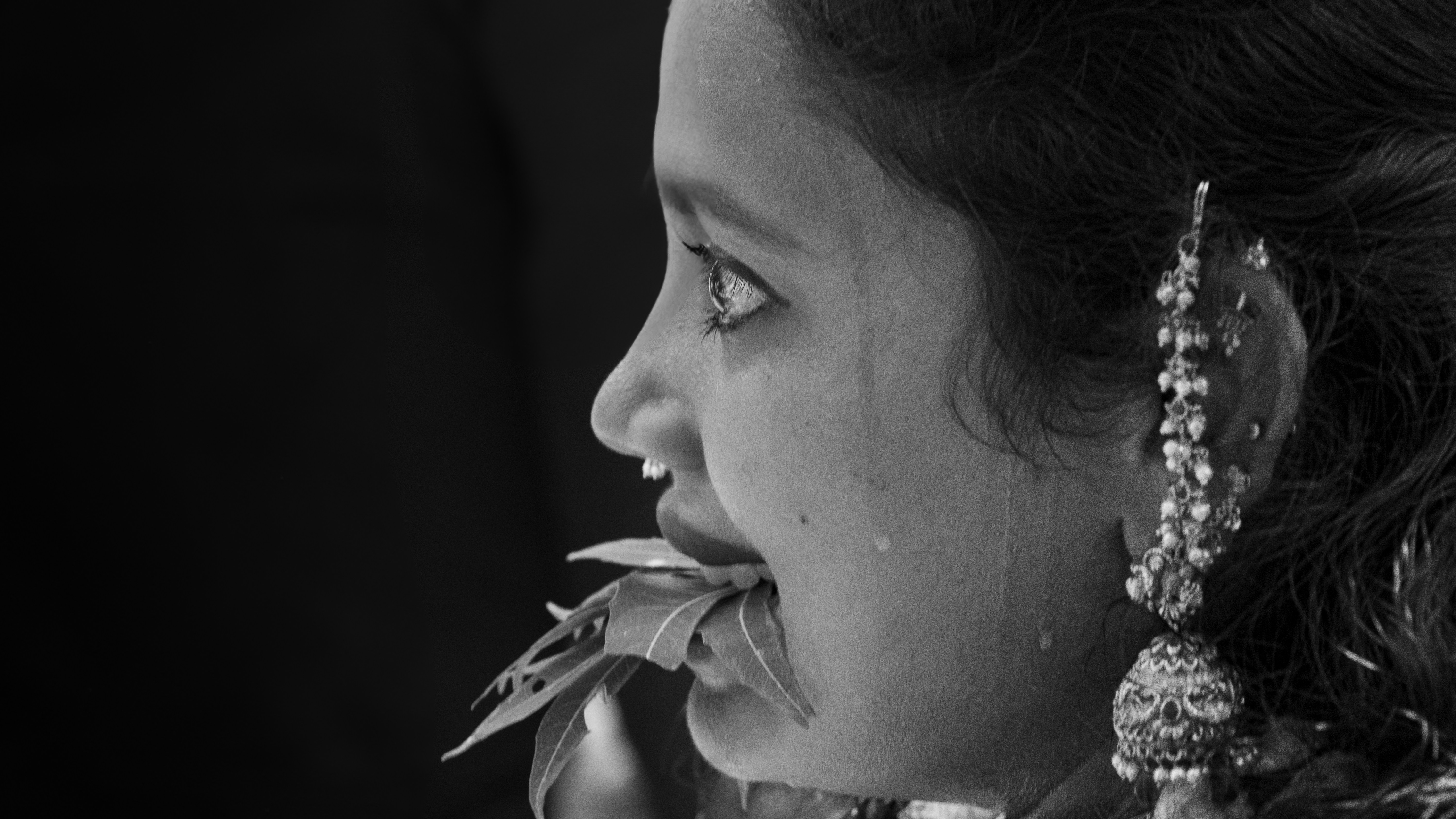 Wanita muda dengan anting-anting berornamen memakan daun