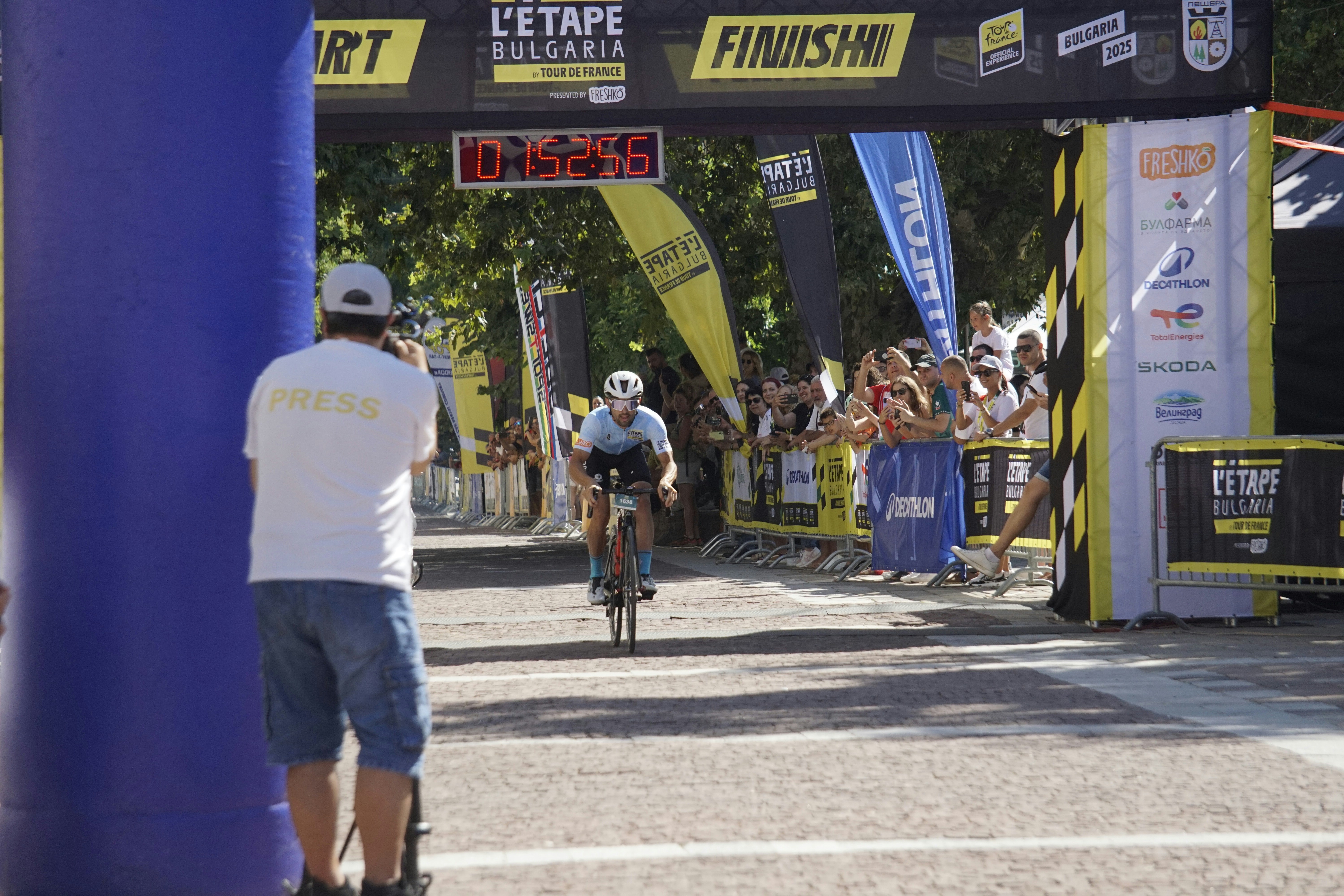 Cyclist crosses finish line with spectators watching