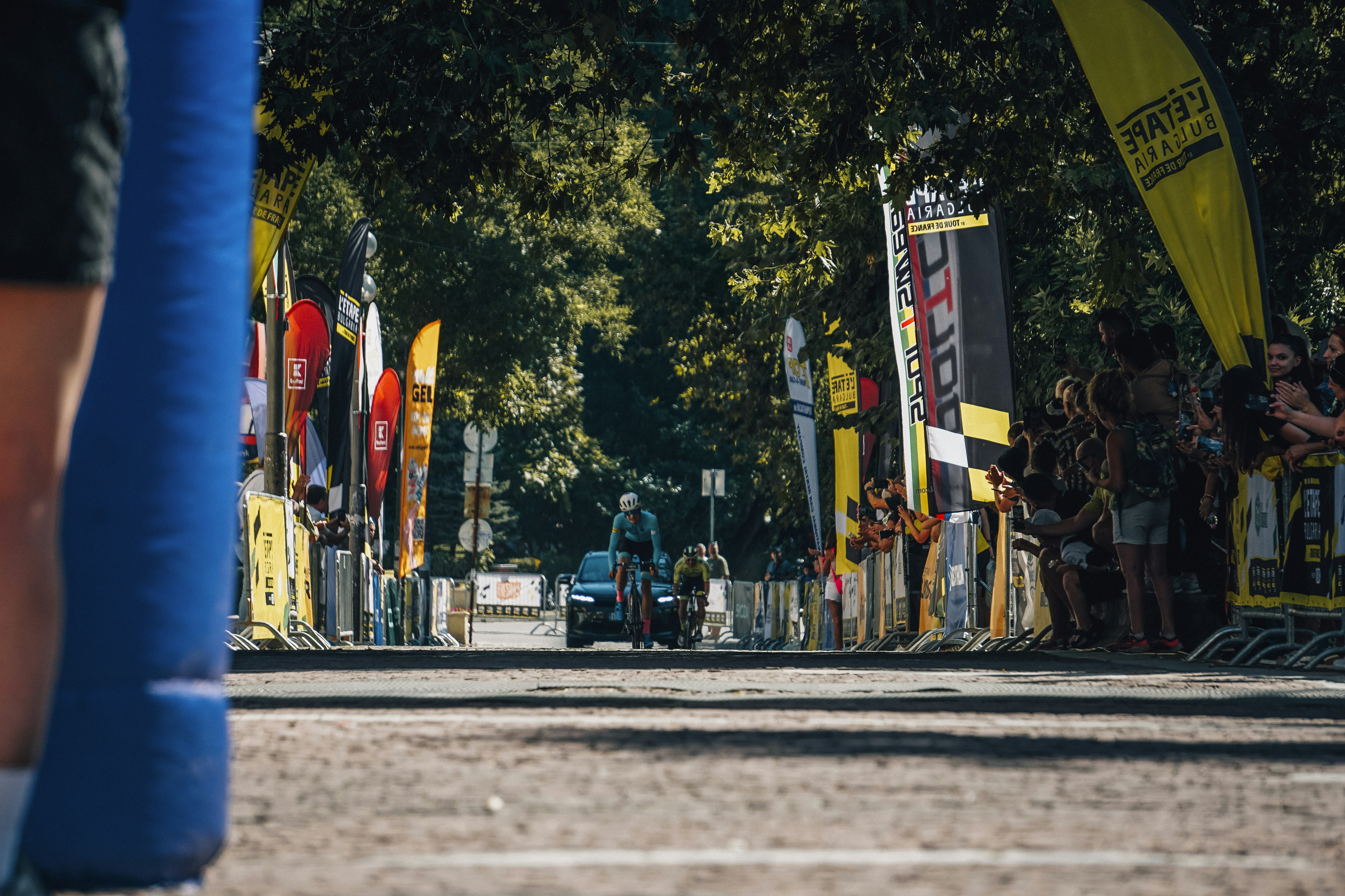 Cyclists race towards the finish line with spectators watching crowd