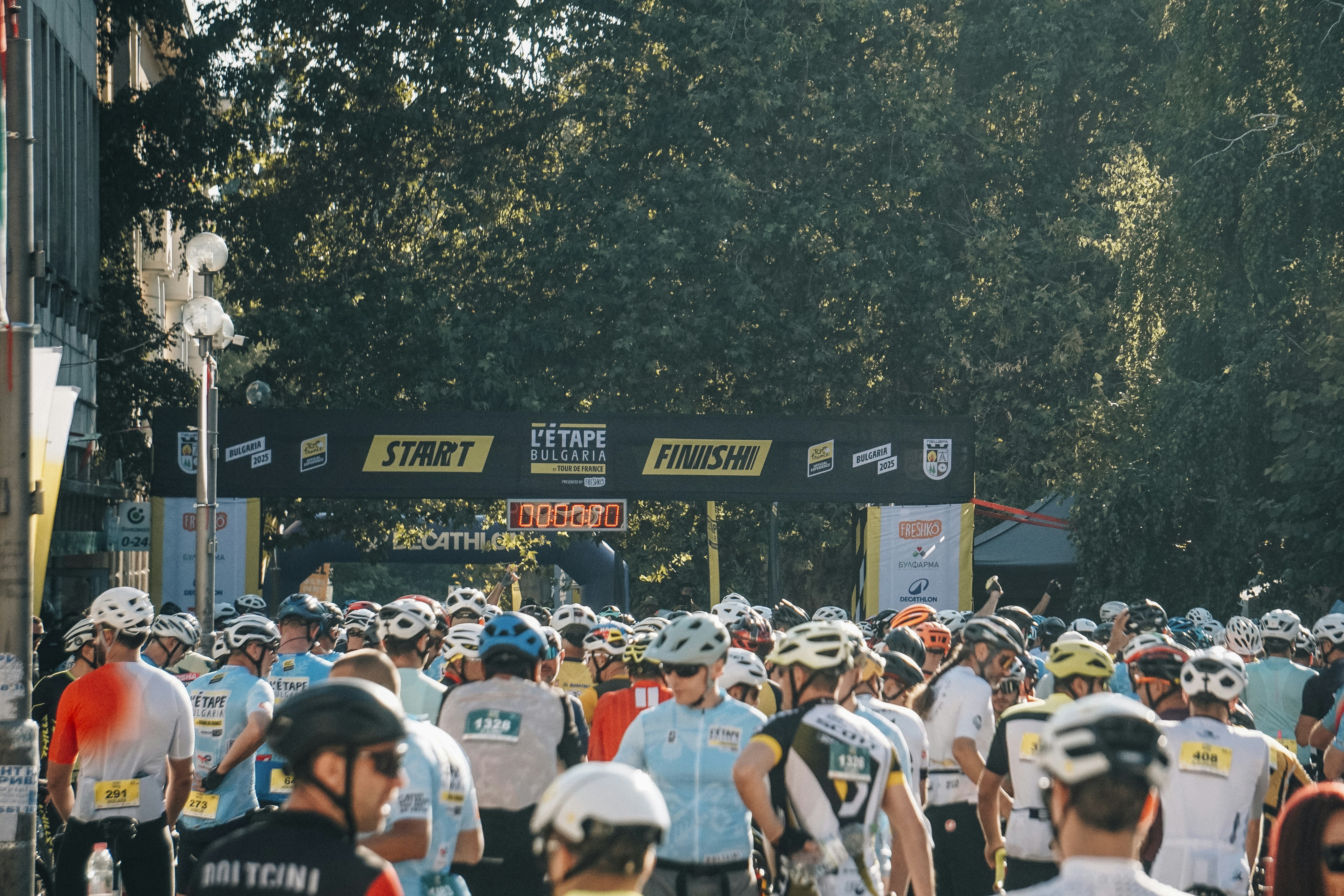 Crowd of cyclists gathered at a start/finish line.