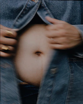Person in denim jacket opening it to reveal stomach