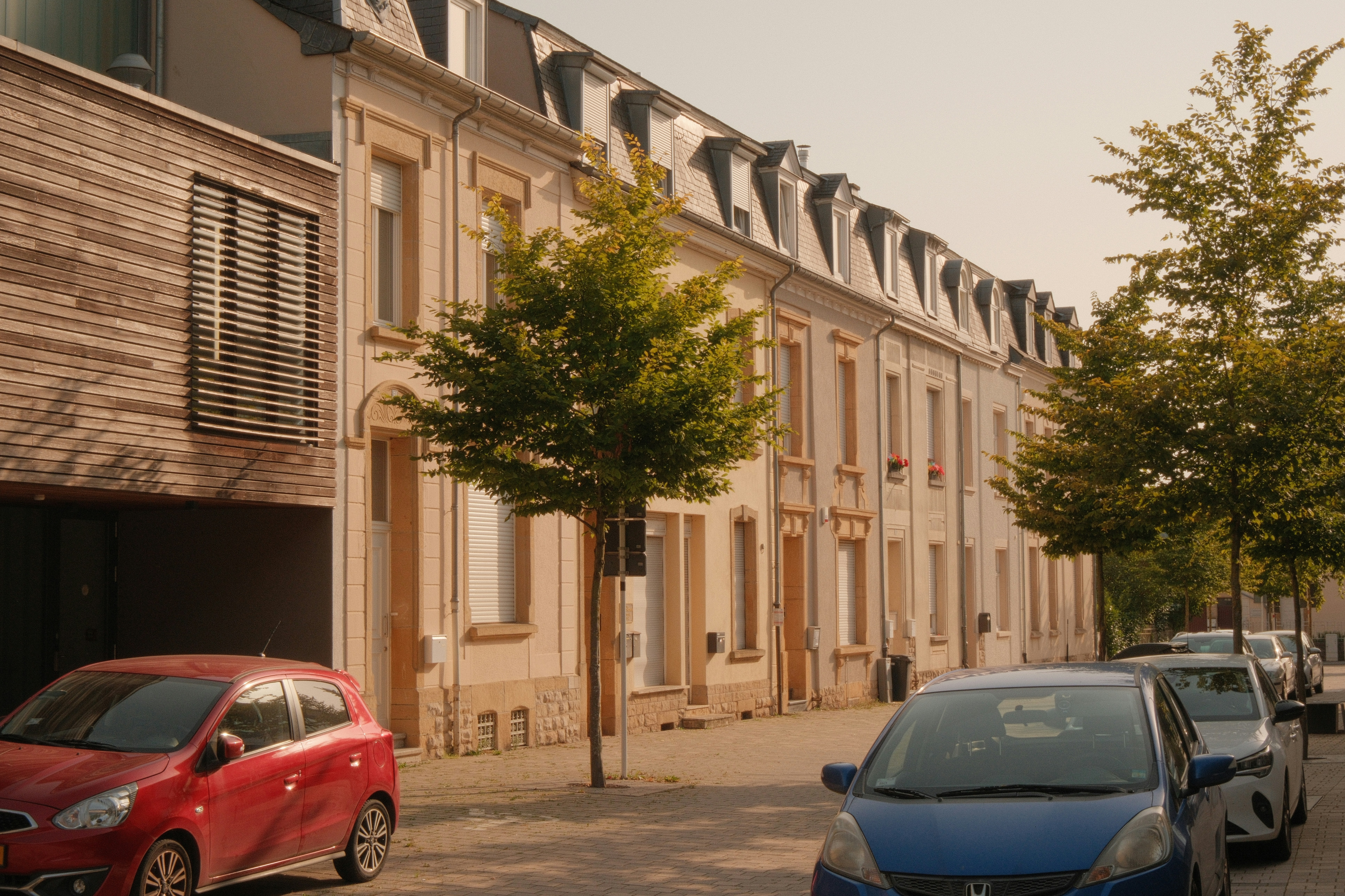 Hilera de casas históricas europeas con coches aparcados.