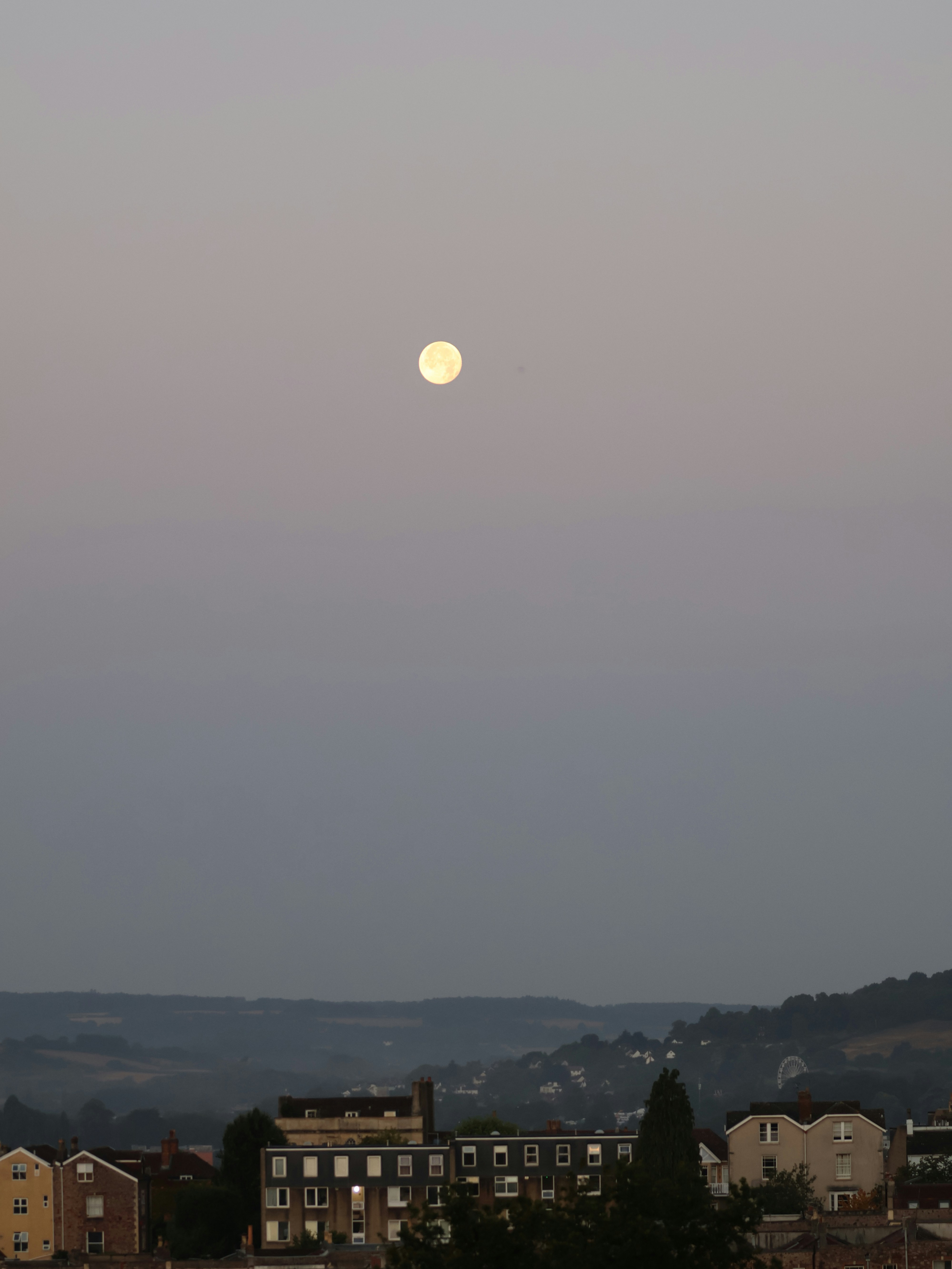 Full moon over buildings at dusk