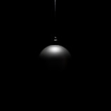 A single black pendant light hangs in darkness