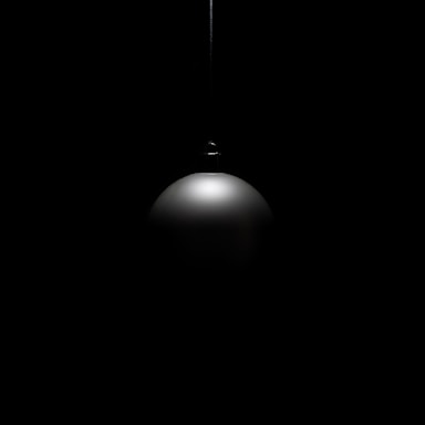 A single black pendant light hangs in darkness