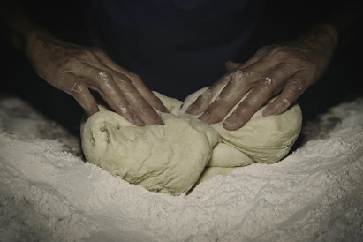 Hands kneading dough dusted with flour