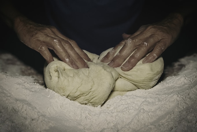 Hands kneading dough dusted with flour