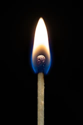 A lit match burning brightly against a dark background