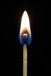 A lit match burning brightly against a dark background